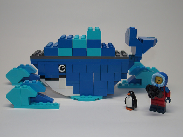 A Lego Docker logo, with a penguin figurine next to a Lego man in a parka.